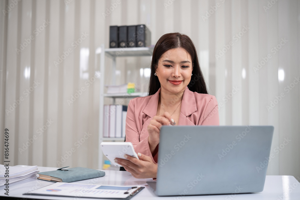 Asian businesswoman working on financial document with laptop on desk in office room Asian businesswoman working on financial document with laptop on desk in office room