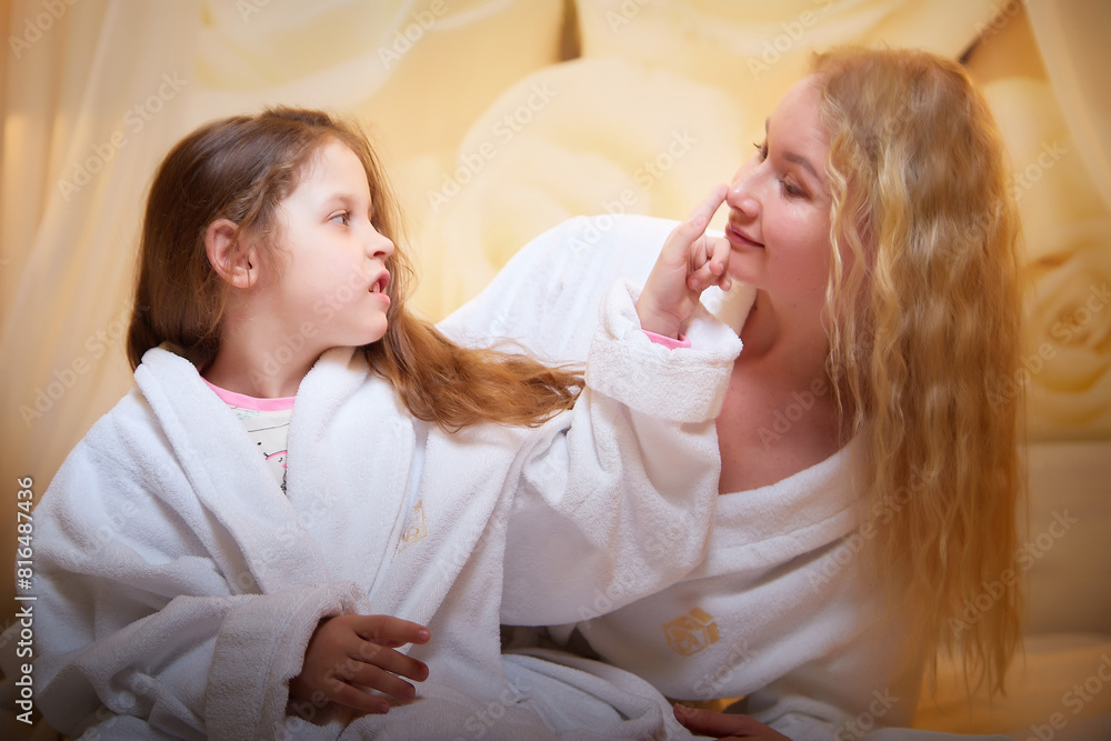 Mother and daughter happily relax and fun together on a bed in bedroom. The concept of tenderness between mom and girl Mother and daughter happily relax and fun together on a bed in bedroom. The concept of tenderness between mom and girl