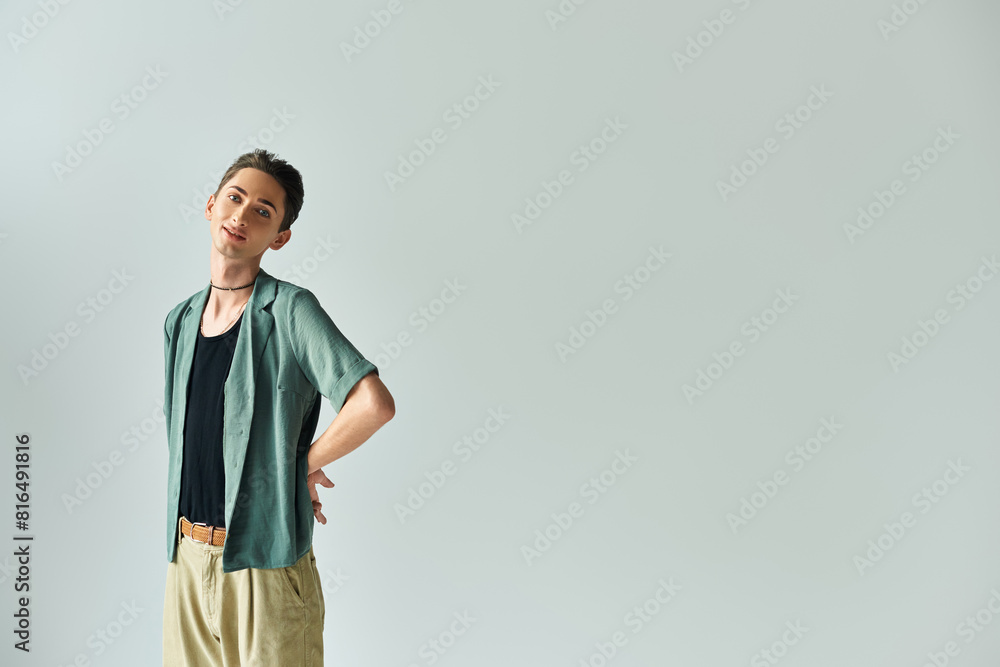 A young queer person confidently posing against a neutral background. A young queer person confidently posing against a neutral background.