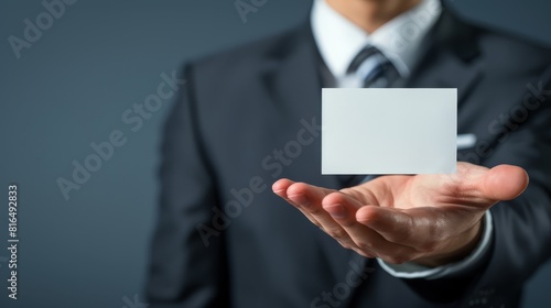 A man in a business suit holds a business card