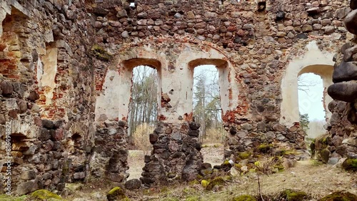 Ruined Old Brick And Stone Walls Of Rauna Castle In Vidzeme, Latvia. drone pullback shot photo