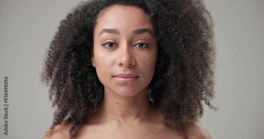 Beauty and healthcare concept - beautiful African American woman with curly afro hairstyle and clear, healthy skin looks at the camera with a calm gaze and smiles a bright toothy smile Beauty and healthcare concept - beautiful African American woman with curly afro hairstyle and clear, healthy skin looks at the camera with a calm gaze and smiles a bright toothy smile