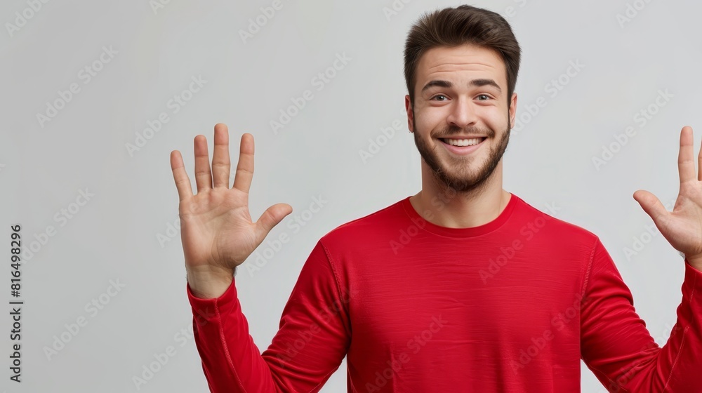 Fototapeta premium A man smiles in a red shirt, hands raised in front of him