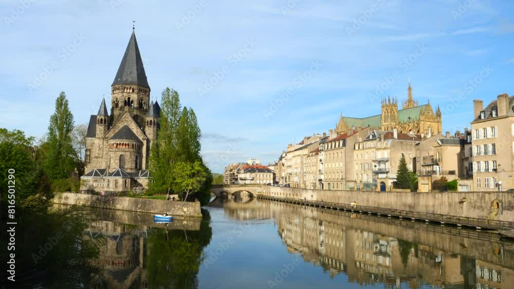 Tranquil river scene in Metz, France with historical a small boat, architecture and a clear sky Tranquil river scene in Metz, France with historical a small boat, architecture and a clear sky