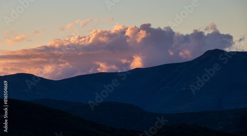 Red dusk clouds over dark rolling hills image in horizontal format