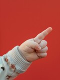The hand of a small child shows one finger up. A small baby hand on a red background.