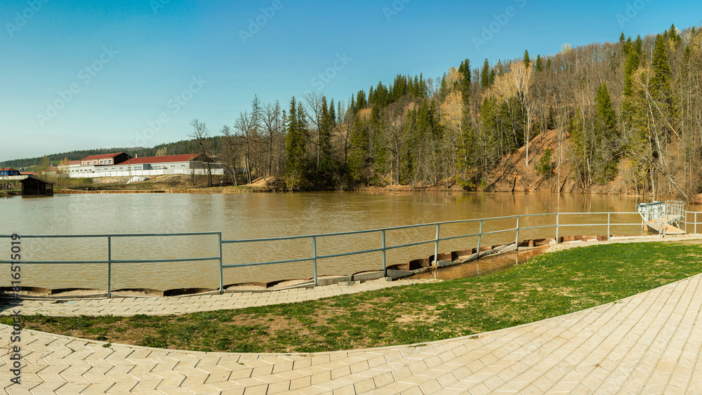 Panorama of the lake and green forest with fir trees in the park in summer in spring. Blue sky. with reflection in water. Park Panorama of the lake and green forest with fir trees in the park in summer in spring. Blue sky. with reflection in water. Park