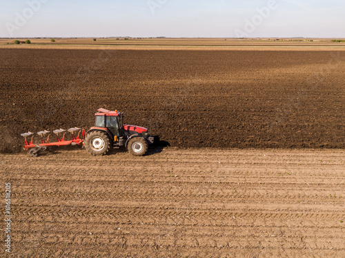 фотографія Aerial view of a tractor plowing rich soil in vast farmland during autumn season