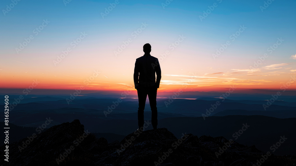 Silhouette of a man in business attire observing the horizon from a high mountain peak at sunset Silhouette of a man in business attire observing the horizon from a high mountain peak at sunset