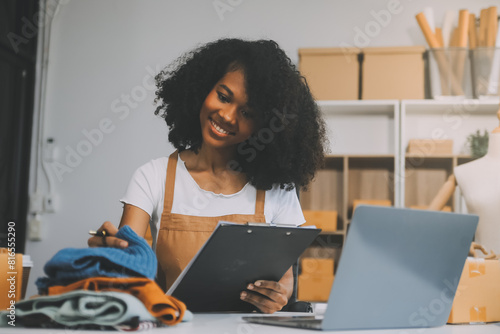 Startup SME small business entrepreneur of freelance Asian woman wearing apron using laptop and box to receive and review orders online to prepare to pack sell to customers, online sme business ideas. photo