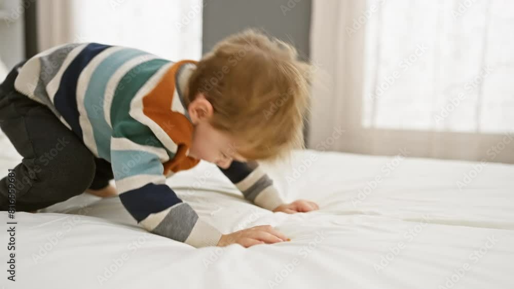 A playful blond boy enjoys his time indoor on a bed in a bright modern bedroom, evoking joy and childhood. A playful blond boy enjoys his time indoor on a bed in a bright modern bedroom, evoking joy and childhood.