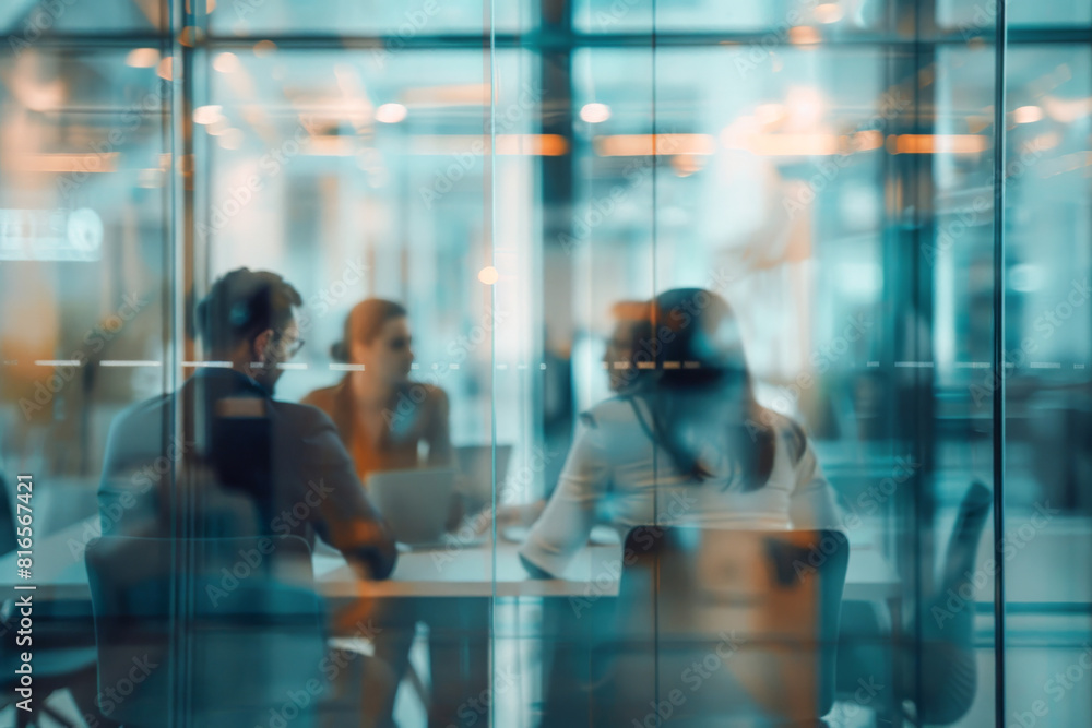 Blurry image of businessmen and businesswomen having a meeting at the table in the office behind transparent glass door Blurry image of businessmen and businesswomen having a meeting at the table in the office behind transparent glass door