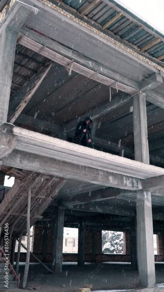 A young man is photographing a landscape on top of an unfinished building A young man is photographing a landscape on top of an unfinished building