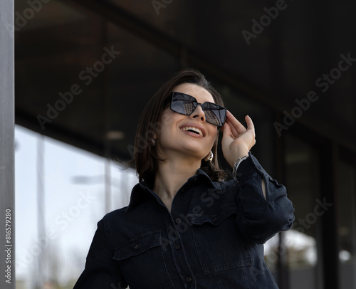 stylish, trendy modern women advertising sunglasses, dressed in modern outfits.girl against his building with large windows.female wear a hat, face close up, portrait.sun eye protection,uv rays