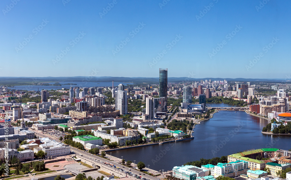 Above view of central part of modern city with skyscrapers and residential buildings. River and bridge on summer day