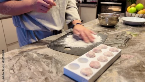 A woman is making cookies on a counter. She is using a rolling pin to flatten the dough photo