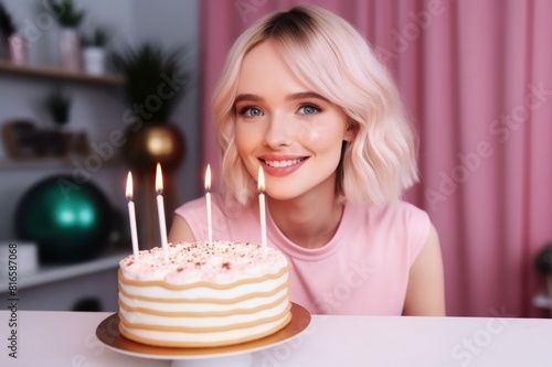 smiling young woman in front of birthday cake on table
