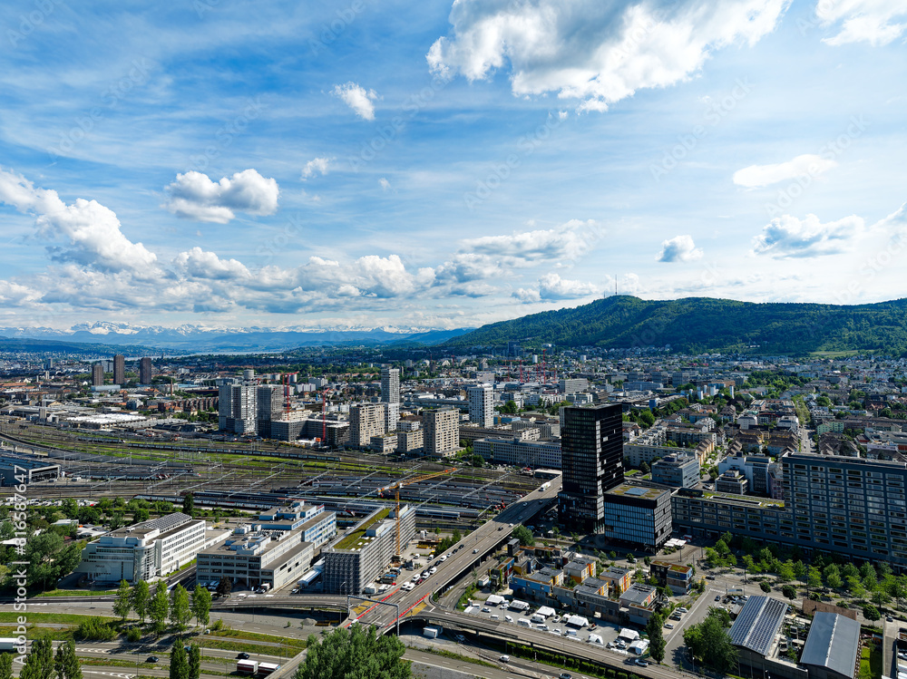 Fototapeta premium Aerial view of District Altstetten with skyscrapers and local mountain Uetliberg in the background at Swiss City of Zürich on a sunny spring afternoon. Photo taken May 14th, 2024, Zurich, Switzerland.