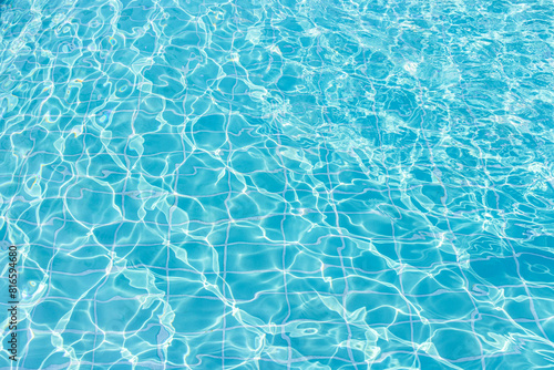 Blue swimming pool water surface and ripple wave background. Summer abstract reflection caustics in swimming pool.