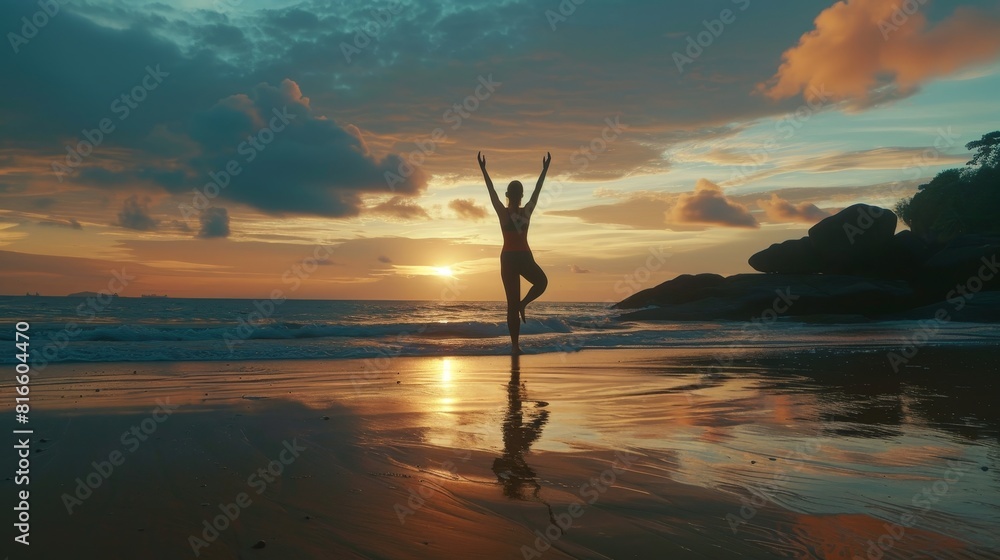 Woman silhouette practicing yoga at sunrise on a peaceful beach