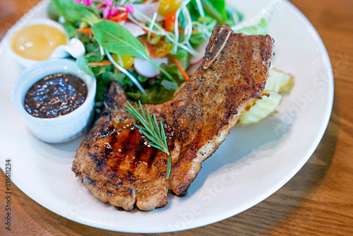 Pork Chop Steak and Organic Salad Put in a white plate on the old wooden table, selective focus, soft focus.
