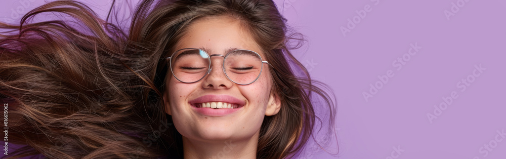 A woman with glasses is smiling as her hair blows in the wind