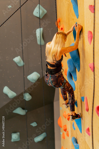 close up at the climbing wall young girl goes down the safety rope, the coach insures against falling