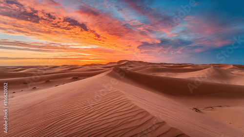 The sun sets over the golden sand dunes in Al-Sukoon Desert  creating a breathtaking view.