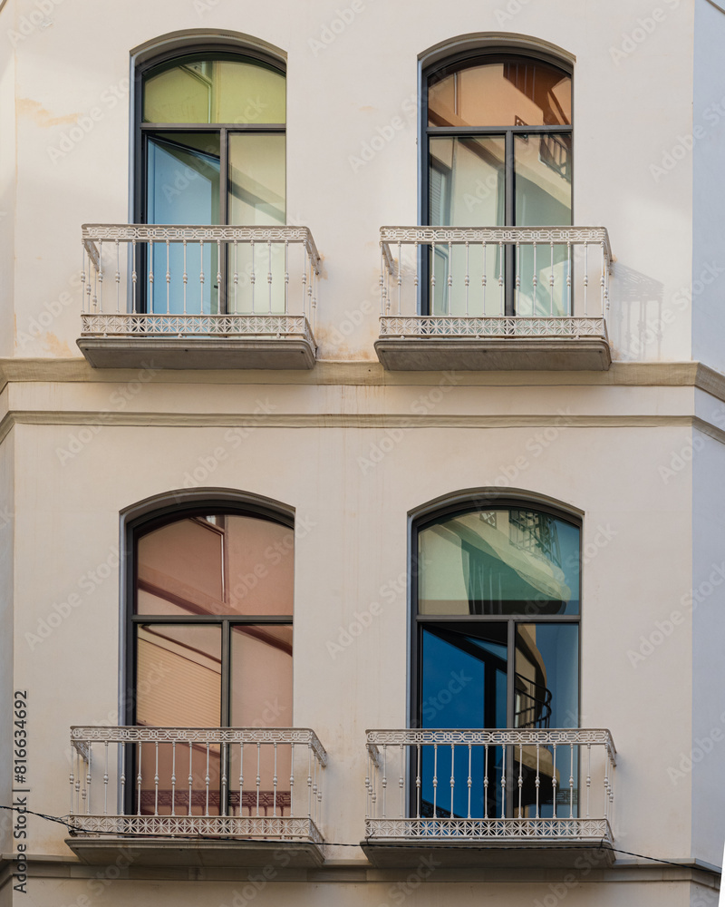 Obraz premium Colorful windows and white balconies on a residential building in Malaga, Andalusia, southern Spain.