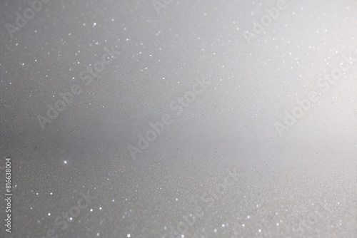 Silver sparkle background with areas of bokeh effect, creating a blurred glitter texture