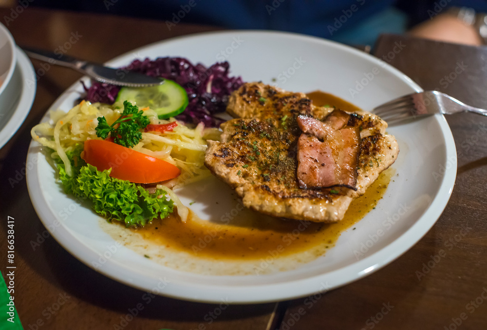 Grilled pork steak with fresh vegetable on white plate in restaurant. Grilled pork steak with fresh vegetable on white plate in restaurant.