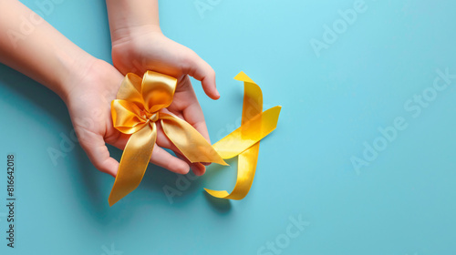 Hands with golden ribbon on color background. Childhood