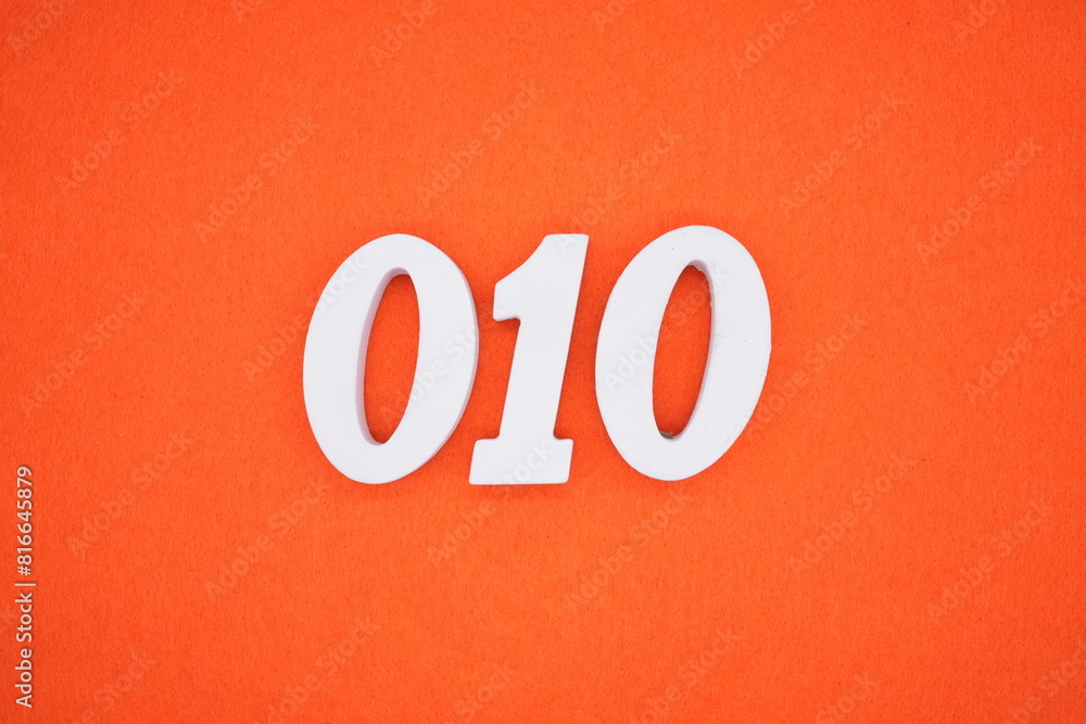 The number 010 is made from white painted wood placed on a background of orange paper. The number 010 is made from white painted wood placed on a background of orange paper.