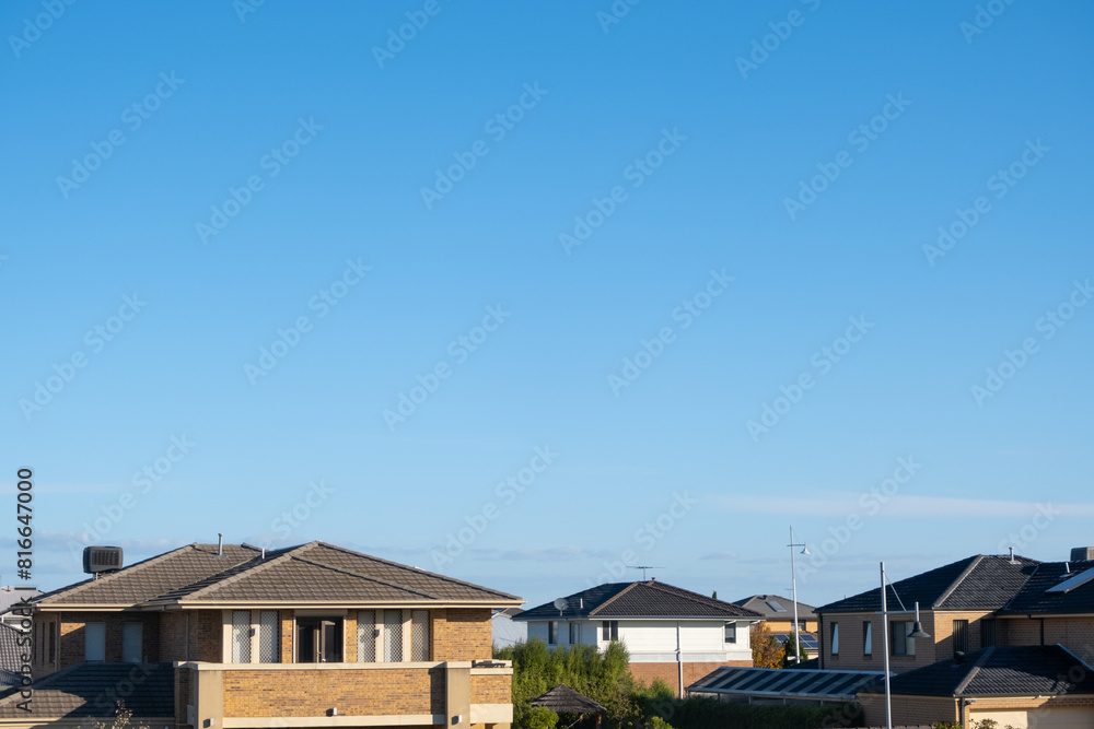 Background texture of two story residential houses against blue sky, with copy space for design. Concept of housing market, real estate development, suburban living, Australian homes and property