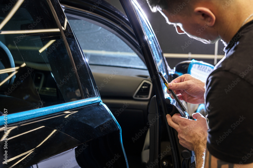 Sticker of a protective film on the headlight of a car in a car detailing studio Sticker of a protective film on the headlight of a car in a car detailing studio