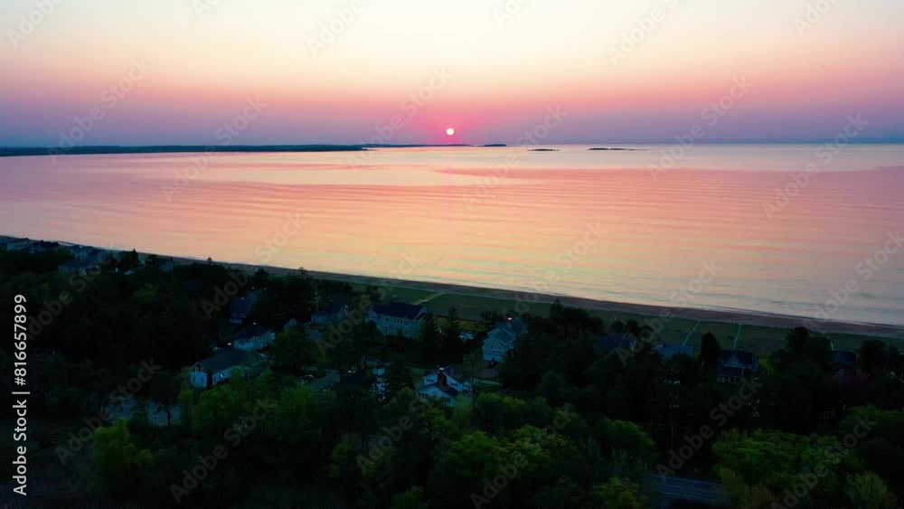 Aerial Drone View of Sunrise over Beach Houses with Colorful Reflections off Ocean Waves and Vacation Homes Along the New England Atlantic Coastline. Colorful Golder Hour Bright Glowing Sky and Sea