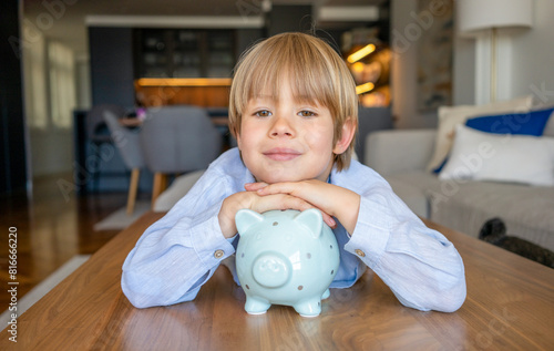 Portrait of cute little boy with piggy bank at home