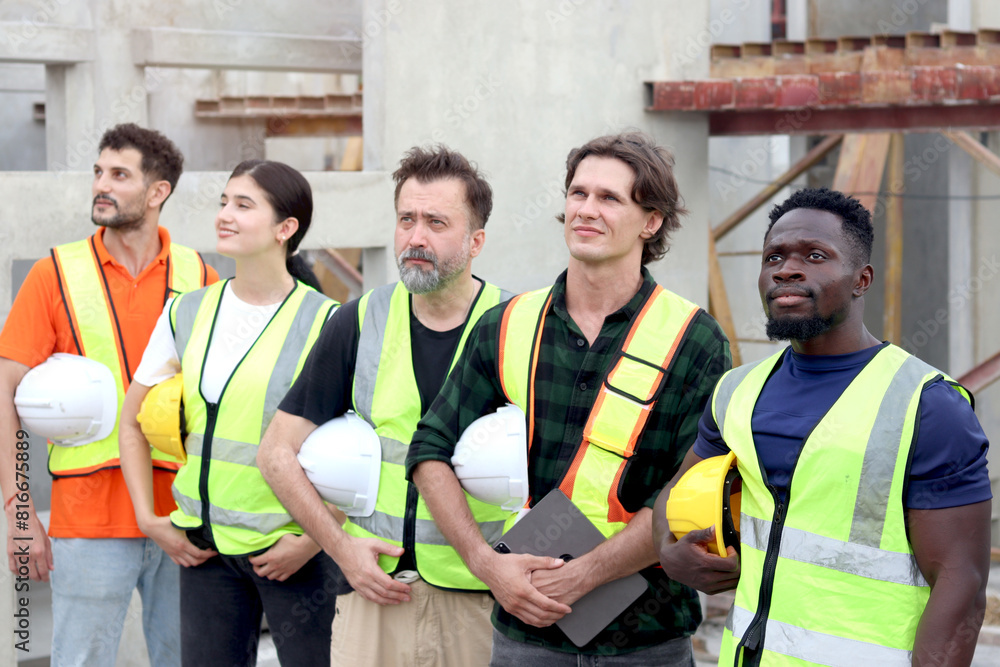© Stella - Group of happy engineer worker team with safety vest and helmet standing with arms crossed in line at construction building site. Construction labor work at workplace. Teamwork unity and diversity