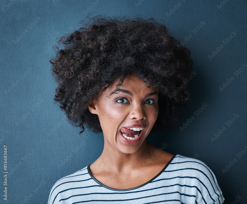 Black woman, emoji and tongue with facial expression in studio for fun, relax and playful attitude on blue background. Lady, comic and goofy portrait with a funny face, crazy and personality isolated Black woman, emoji and tongue with facial expression in studio for fun, relax and playful attitude on blue background. Lady, comic and goofy portrait with a funny face, crazy and personality isolated