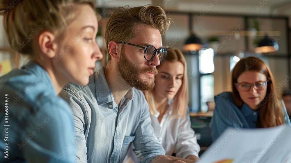Young businessman looking at data piece of partner in co-working space in office. Young businessman looking at data piece of partner in co-working space in office.