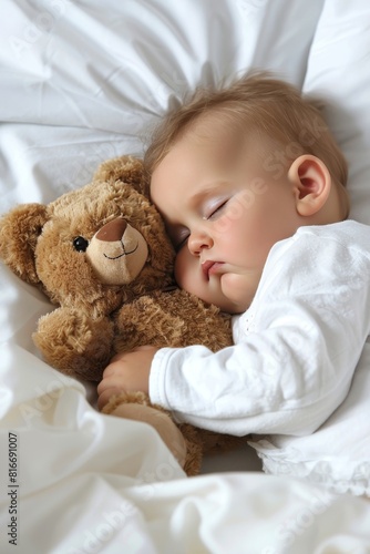 Sweet baby boy in adorable bear jumpsuit peacefully sleeping with teddy bear in cozy bed