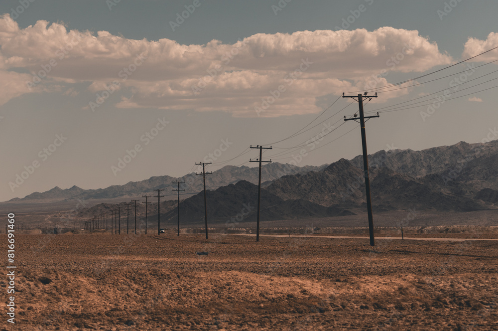 Rural landscape with a cloudy sky and a field with power lines ...