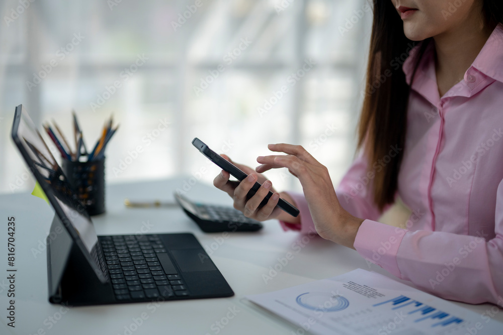 A woman is sitting at a desk with a laptop and a cell phone A woman is sitting at a desk with a laptop and a cell phone