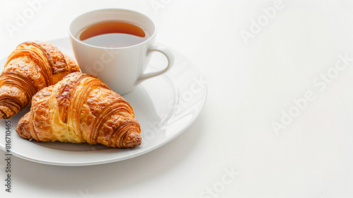 Plate with delicious croissants and cup of tea on white