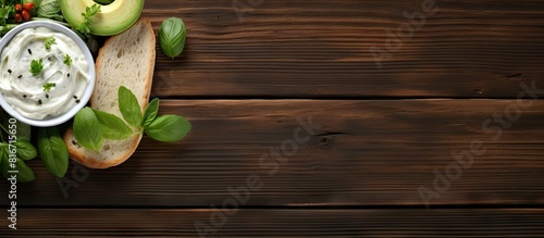 A vegetarian themed composition with an avocado and cream cheese sandwich accompanied by celery sticks and basil leaves The brown wooden background provides ample room for adding text Copy space imag