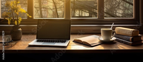 A well illuminated desk positioned by the window capturing the sunlight The desk showcases a laptop notebook and an assortment of writing instruments offering ample copy space photo