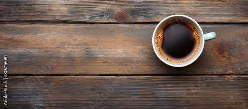 Top down view of a cup of fragrant coffee resting on a rustic wooden table with ample room for text in the background