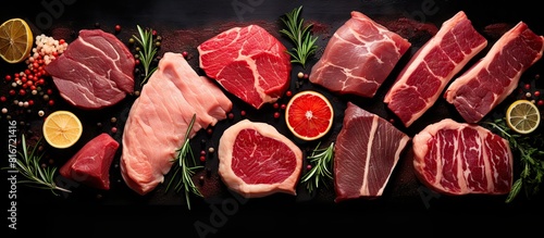 Copy space image of a top view of a variety of raw steaks including salmon beef pork and chicken placed on a black background