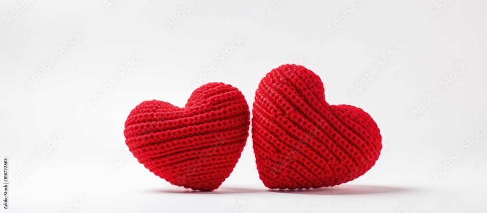 Two red knitted hearts are showcased against a white background presenting a delightful concept for celebrating Valentine s Day The composition provides ample copy space for additional elements or te Two red knitted hearts are showcased against a white background presenting a delightful concept for celebrating Valentine s Day The composition provides ample copy space for additional elements or te