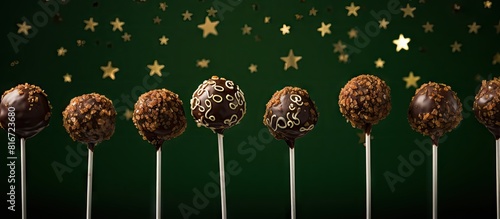 A wide screen copy space image of Christmas dessert round brownie cake pops topped with stars on a dark green background It captures the concept and scene of Christmas food dessert with a holiday bor photo